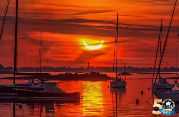 An eclipse rising in the morning over Rowayton Harbor with boats in the foreground. Photo WAS member Dana Weisbrot