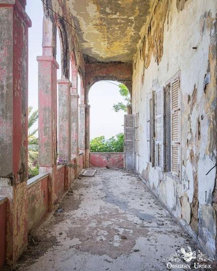 photo of ruined walkway, red walls with peeling paint