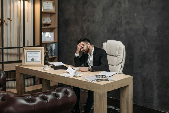 Image of man at desk holding hand to head by Pavel Danilyuk via Pexels