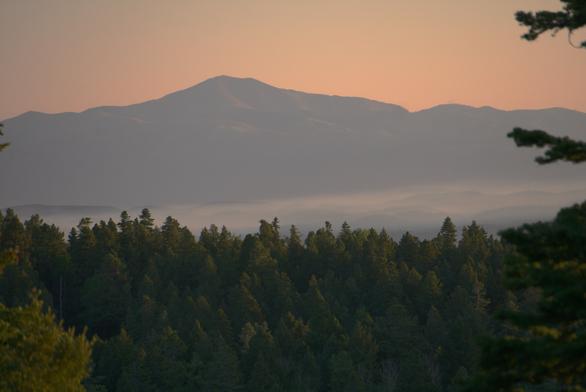It well after sunrise, but the air is pink-orange...because of distant smoke from the Trout fire near Silver City.

Low lying smoke from the Seven Springs fire blankets the mountainous terrain at 8,000 feet elevation.

Sierra Blanca peak, almost 12,000 feet at the summit, looks gloomy and dark.

Foreground conifers also have subdued lighting.