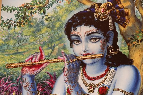 An unknown artist's depiction of Krishna, in a verdant green wood, playing the flute. He is blute-skinned with red henna all over his hands, his wrists, the backs of his hands, above his eyebrows, and down his cheeks. He wears floral necklaces and necklaces of gold, and has an intricate armband.