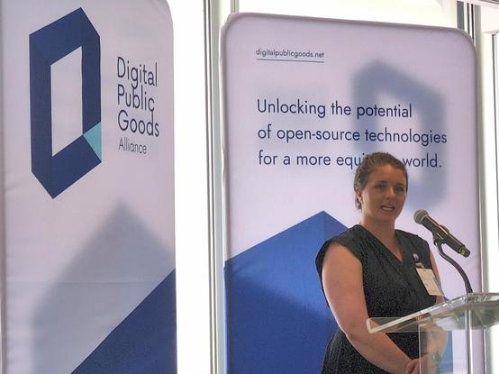 Speaker at podium in front of Digital Public Goods Alliance banner.