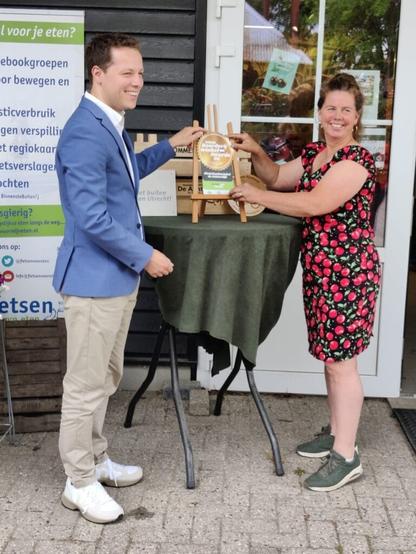 Onno reikt een award uit aan Eveline Westeneng, eigenaar van boerderijwinkel De Achterdijk,
