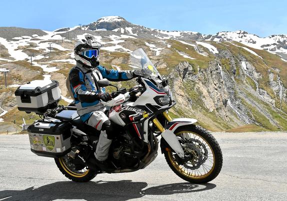 a motorcycle passing by, in the background rocky alps