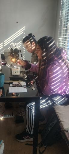 Fotografía de sesión del taller Jaqueo Textil, en la imagen dos personas mujeres están haciendo aseo profundo a una máquina de coser doméstica.