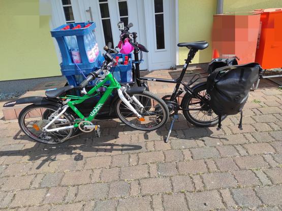 Muli Lastenrad mit 3 leeren Wasserkästen im Korb und einem woom 4 an den Korb angehängt
