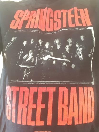 (Teil)Selfie: T-Shirt mit schwarz-weiß-Foto von Bruce Springsteen und der E Street Band, oben drüber in rotorange "Springsteen", unten drunter ebenfalls in rotorange "E Street Band".