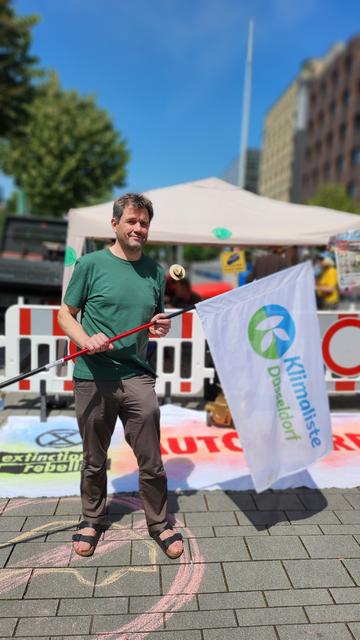 Zu sehen ist Christopher Schrage, der die Fahne der Klimaliste Düsseldorf hält.