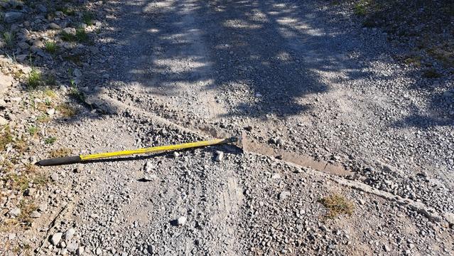 The gravel driveway, over the dry months, has filled the water swales/bars with gravel. That's acceptable during drought.

Monsoon is coming, and there will be flash floods. I'm using a hoe (yellow handle) to clear out the drainage paths. This will minimize erosion straight down the sloped driveway.