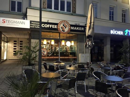 Outdoor seating area in front of a coffee shop called "Coffee Maker".
