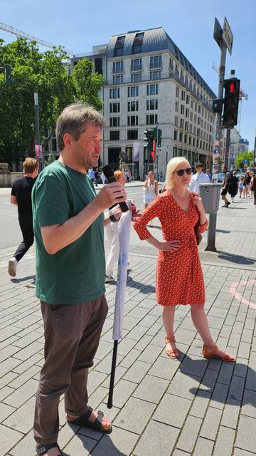 Christopher Schrage (Klimaliste) erklärt während der Kundgebung, dass diese lediglich den längst getroffenen Ratsbeschluss umsetzt. Clara Gerlach (Bündnis 90 / Die Grünen) hört angeregt zu.