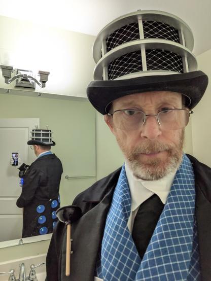 A mirror selfie of man wearing tails, a waistcoat, a top hat and carrying a walking stick all carrying the design language of a Dalek. The picture shows the back in the mirror with Dalek dots on them
