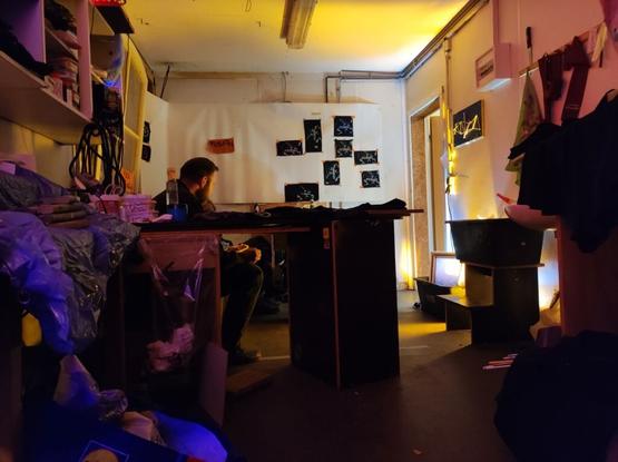 an improvised artelier, with yellow light and patches in the back, dark furniture in the middle and blue areas in the bottom left foreground corner