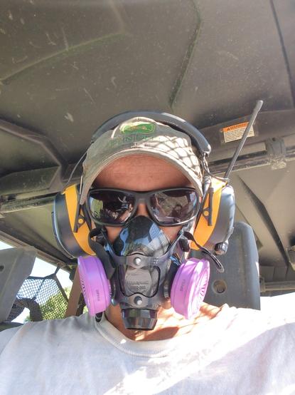 Me, looking like a wannabe fighter pilot, with the respirator, and the safety sunglasses, and the earmuffs.  John Deere hat because it was free, and I need literally any hat because I'm bald, and my head will burn otherwise.