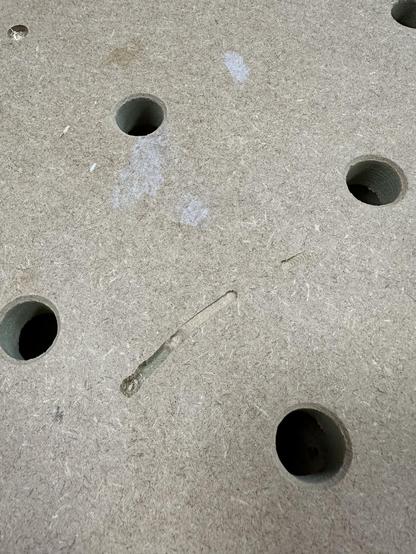 A MDF workbench top with bench dog holes and a gnarly gauge left by a 6mm router bit going AWOL from the machine.