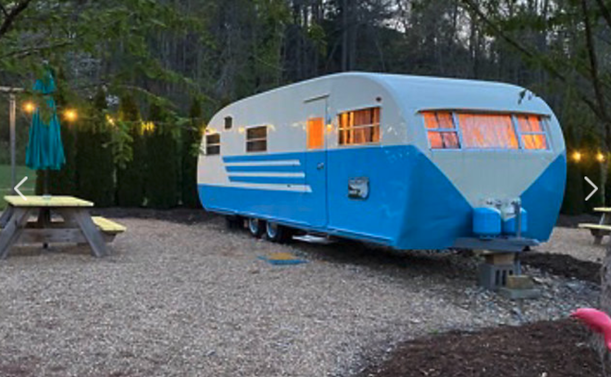 A restored 1950's trailer, part of a property with 10 of them, near Asheville.

This is a "Spartan" found in AZ for people who know those kinds of things.  It is 2-toned blue, and sits on a gravel area, with a picnic table.