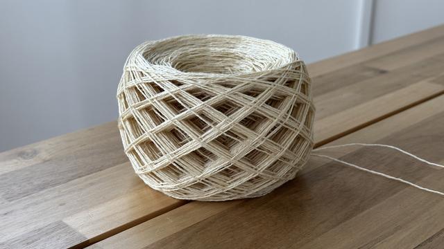 Linen yarn that has been mechanically balled. The way it formed as the ball was created made a pattern of diamond shaped windows all around it.