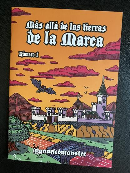 Un ejemplar de Más allá de las tierras de la Marca. Un pequeño fanzine rolero con uan portada preciosa en la que un castillo al lado de un río está siendo sobrevolado por un dragón. Los colores son vivos y el trazo grueso, dando mucha energía a la ilustración.