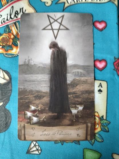 Card from the Heaven and Earth Tarot deck.
Five of Cups. 
A person wearing a black cloak, head down, crestfallen, looking at three spilled cups. But there are still two cups full behind him.