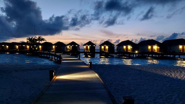 View of a set of over water suites on a dock in the Maldives at dusk