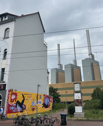 Graffiti op gevel met tekst: catcalls are over in Hannover. Daarnaast schoorstenen van electriciteitscentrale.