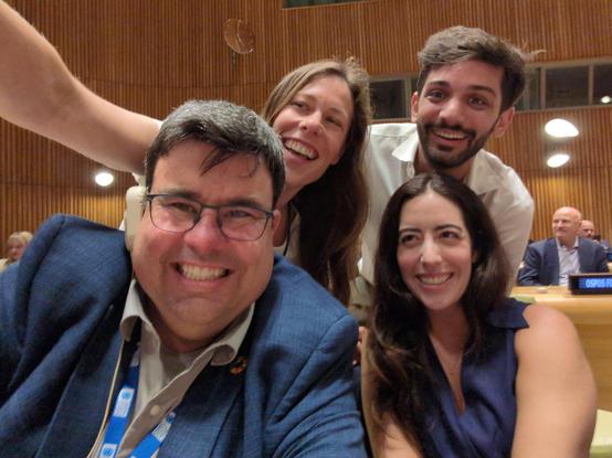 Four crazy folks smiling in a selfie in the UN Trusteeship Council chamber.