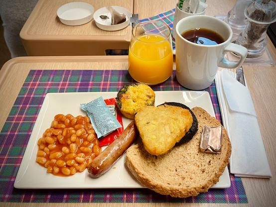 Full Scottish breakfast in the Club Car 
Rectangular plate with beans, sausage, a hashbrown with some other items hidden underneath it, a mini frittata, and a slice of toast