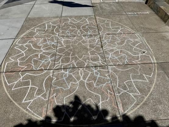 A large mandala drawn on the ground using chalk. This is by the same chalk artist as the previous photo and is only ten feet away. This mandala is about 6 feet wide.