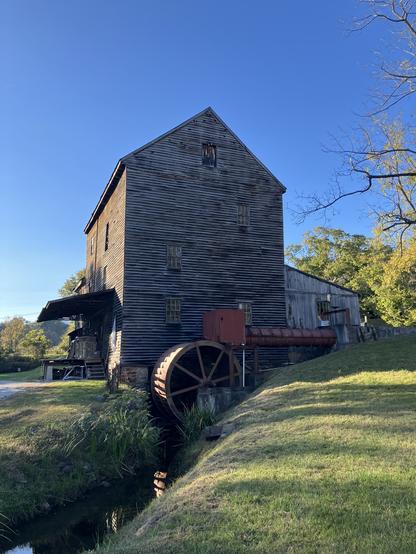 a four-story wooden building rises above a large water-wheel and stream; it's a water-powered flour mill built in the 1700s, and looks like an artifact from another time