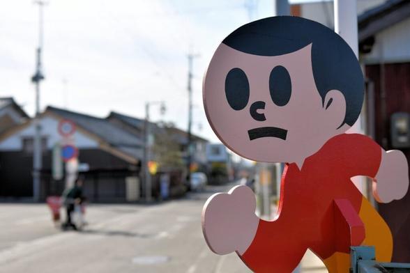 Tobidashibōya cutout - a booy with large round eyes and a solemn expression - running from the right side of the screen