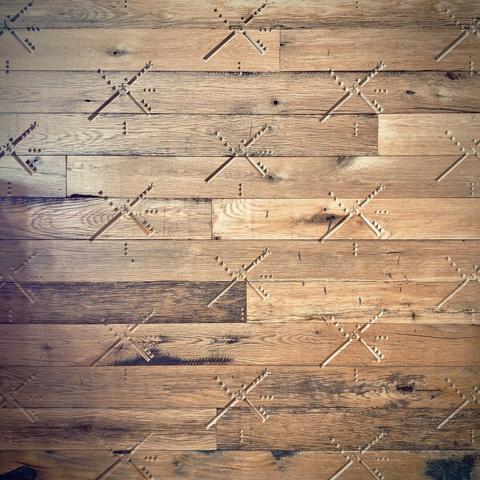 The Portland International Airport classic blocky airstrip design takes on a windmill form with miniature Dutch Bros logos inside it, as it tiles out in a stamped, recessed pattern across a wall of wooden planks.