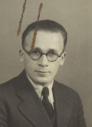 Black and white portrait of a man wearing glasses and a suit.