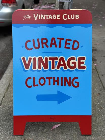 A bold A-frame advertising a vintage store painted in bright blue and red with big, chunky block letters