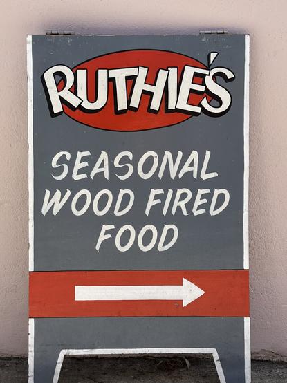 A simple A-frame advertising a food truck, painted in gray and red with white lettering.