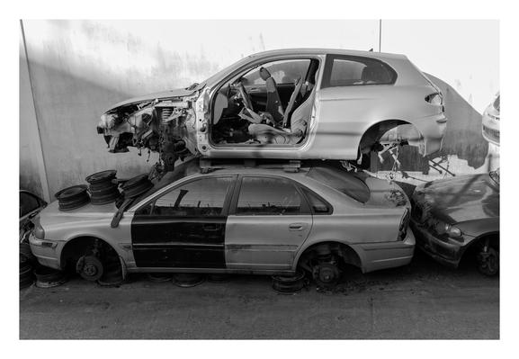 Deux carosseries de voiture empilées l'une sur l'autre. Celle du haut n'a plus de portières, ni de roues; la seconde n'a plus de pneus. Les deux anciens véhicules sont recouverts de poussière.