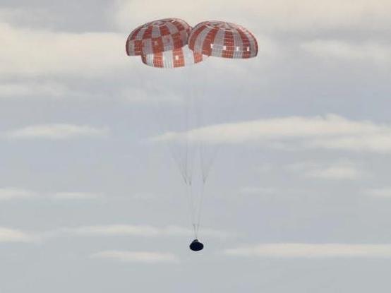 A photograph of Artemis 1 parachuting as it returns to earth from it's successful mission.