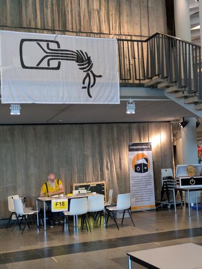 Bild zeigt Dave am Stand des Chaos Treffs obendrüber große Chaos Flagge.  Nebenan sieht man den Stand der Computertruhe.