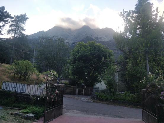 Photo d'une entrée d'hôtel avec une montagne et un nuage accroché au sommet derrière