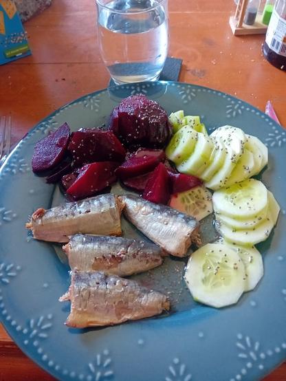 Betteraves rouges, concombre et sardines a l huile dans une assiette bleue