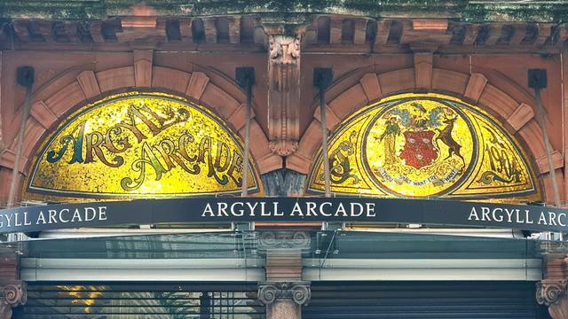 Mosaics made with metallic golden tiles over the entrance to a Victorian shopping arcade in Glasgow.