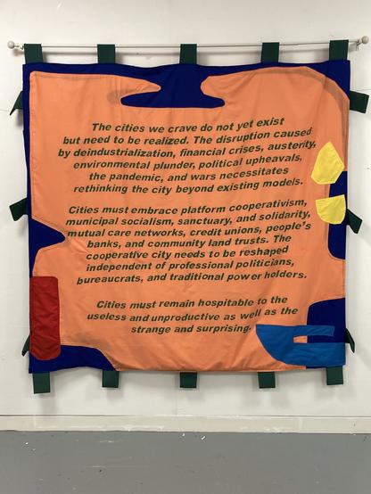 Photograph of a banner consisting of black words on an orange background.
