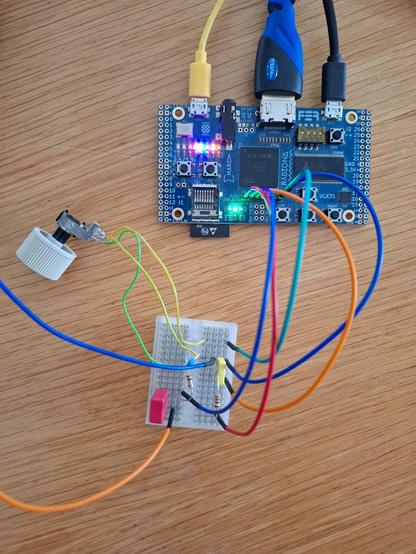Hardware setup for the SDR in 1-bit conversion mode. Two USB cables are connected to the ULX3S board, along with a HDMI monitor cable and jumper wires to a small breadboard on which a few passive components for oversampling 1-bit analog-digital conversion using the LVDS comparator of a differential pair. The variable resistor is for setting the DC offset. Two jumper wires leave the image, the orange one carrying signal from the antenna preamp and blue for ground. One could also connect these two wires directly to the FPGA board, using the on-board 12 bit MAX11125 ADC converter.