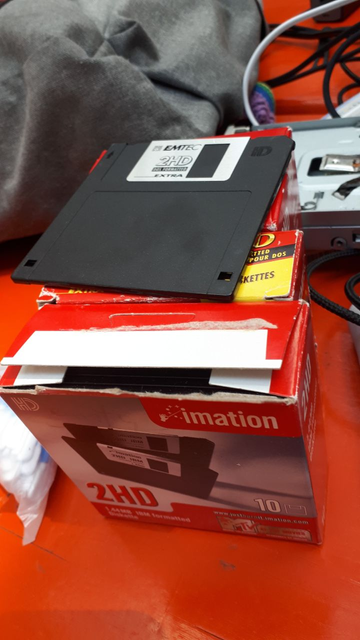 a 3.5 inch floppy disks on 4 boxes a 10 of floppy disks. In the background there is a floppy drive partially visible