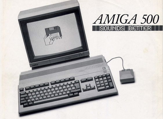 Black and white picture of a computer, slightly tilted to the left, with integrated keyboard, computer display showing a hand holding a diskette, a mouse. Headline »AMIGA 500« and »SOUNDS BETTER«