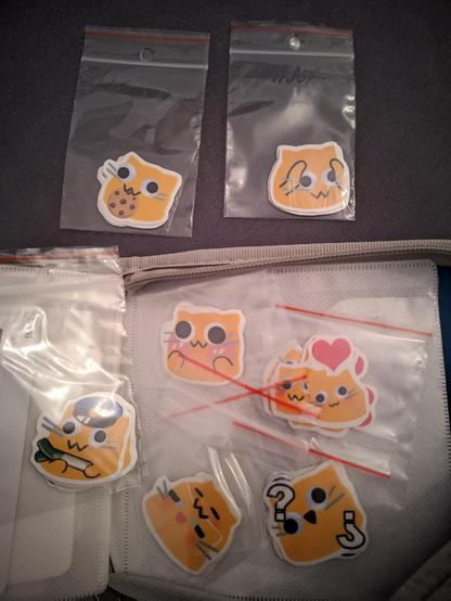 Blobcat stickers organized in small plastic baggies in a CD organizer.