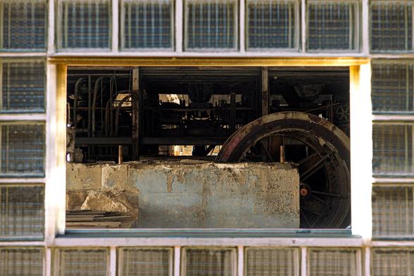 Looking inside through a missing window at an old and rusting factory