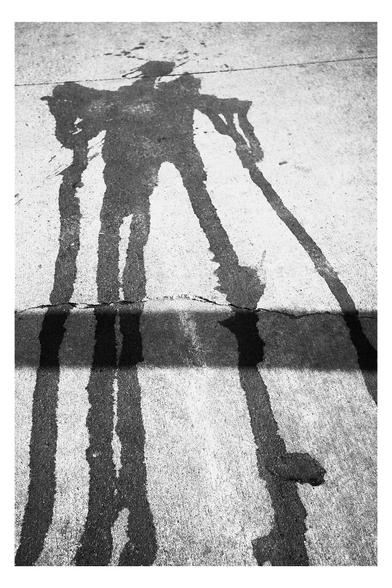 Liquid stain on pavement that looks like the body of a monster (or its shadow.)