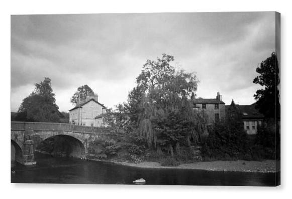 Black and white film photograph of an old stone bridge over a river.  The image is shown printed upon a box canvas.