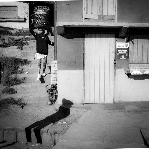Une personne descendant un escalier avec un gros panier sur la tête.