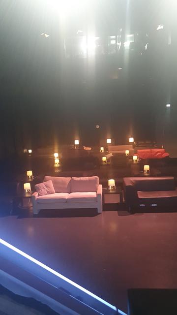 Bild von der Bühne auf viele Sofas. Dazwischen schwarze Tischchen und Lämpchen